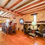 Rustic dining area with exposed beams and stone walls.
