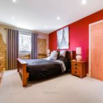 Cosy bedroom with wooden furniture and red accent wall.