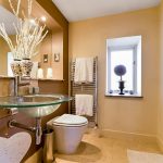 Modern bathroom with glass sink and towel rack.