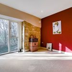 Modern room with stone wall and large windows.