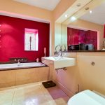 Modern bathroom with red accents and large mirror.