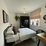 Modern minimalist bedroom with desk and decor.