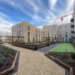 Modern residential building with gardens and crane.