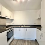 Modern white kitchen with black worktops.