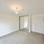 Empty room with mirrored wardrobe and white walls.