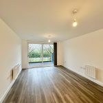 Spacious empty room with wooden floor and large window.