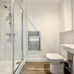 Modern bathroom with shower, toilet, and sink.