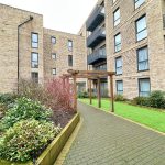 Modern building courtyard with gardens and path.