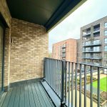 Modern balcony overlooking apartments and garden courtyard.