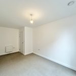 Minimalist empty room with white walls, carpeted floor.