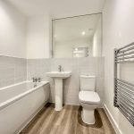 Modern bathroom with bath, toilet, and sink.