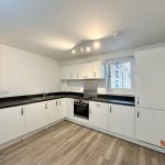 Modern white kitchen with wooden flooring and window