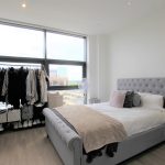 Modern bedroom with large window and grey bed