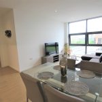 Modern living room with large windows and TV.
