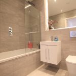 Modern bathroom with grey tiles and white fixtures.