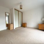 Empty bedroom with wardrobes and wooden drawers.