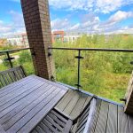 Balcony view over grassy area and modern buildings.