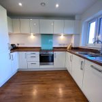 Modern kitchen with white cabinets and wooden floor.