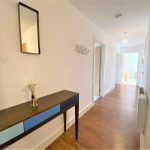 Modern hallway with wooden floor and console table.