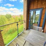Balcony with countryside view, wooden table and chairs.