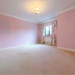 Empty pink room with window and floral curtains.