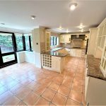 Spacious kitchen with large windows and tiled floor.
