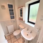 Small bathroom with sink, toilet, and window.