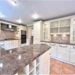 Modern kitchen with white cabinets and granite countertops.