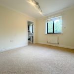 Empty bedroom with window and carpeted floor.
