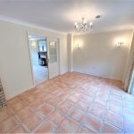 Empty room with chandelier, tiled floor and patio doors.