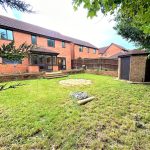 Spacious garden with brick house and shed.