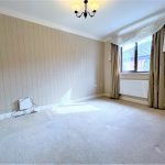 Empty carpeted room with window and curtains.