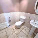 Small bathroom with tiled walls and white fixtures.