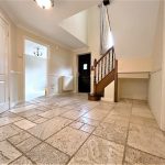 Spacious hallway with staircase and tiled floor.