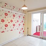 Room with floral wallpaper and sliding glass doors.