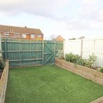 Small garden with artificial grass and wooden fence.