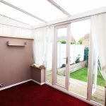 Empty sunroom with glass doors to garden.