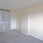 Empty carpeted room with built-in wardrobes.