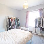 Bedroom with clothes racks and white bedding