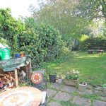 Leafy garden with patio, shed, and picnic table.