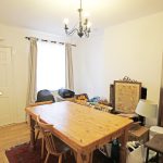 Cluttered dining room with wooden table and chairs.