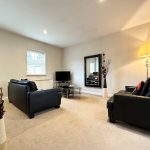 Modern living room with black sofas and TV.