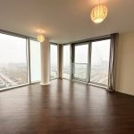 Spacious room with large windows and wooden floor.