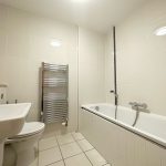 Modern white bathroom with tub and heated towel rail.