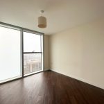Empty room with wooden floor and large window.