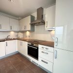 Modern kitchen with white cabinets and appliances.
