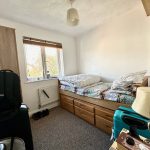 Compact bedroom with single bed and suitcase.