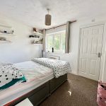 Cosy bedroom with polka dot bedding and shelves.