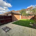 Sunny back garden with a lawn and patio.