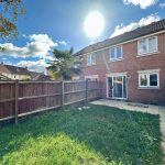 Sunny backyard with grass and brick house